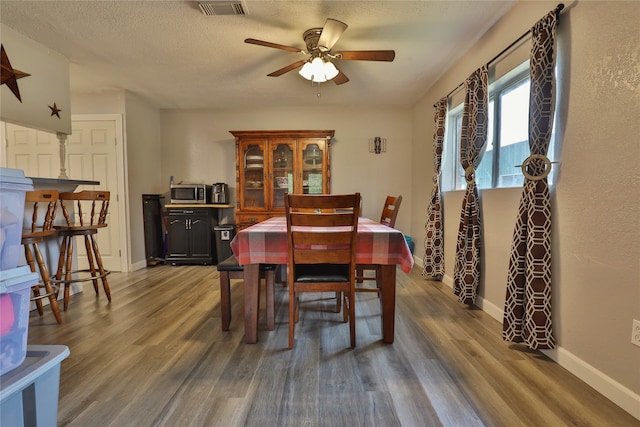 dining space with ceiling fan, a textured ceiling, and hardwood / wood-style floors