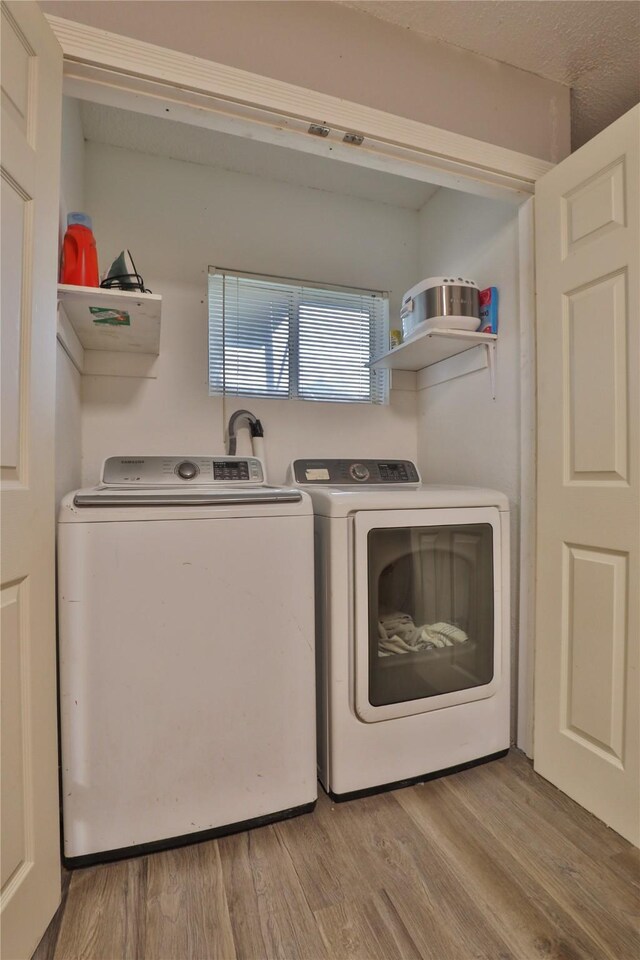 clothes washing area featuring light wood-type flooring and independent washer and dryer