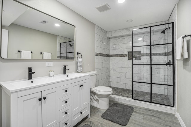 bathroom with hardwood / wood-style floors, vanity, toilet, and a shower with door