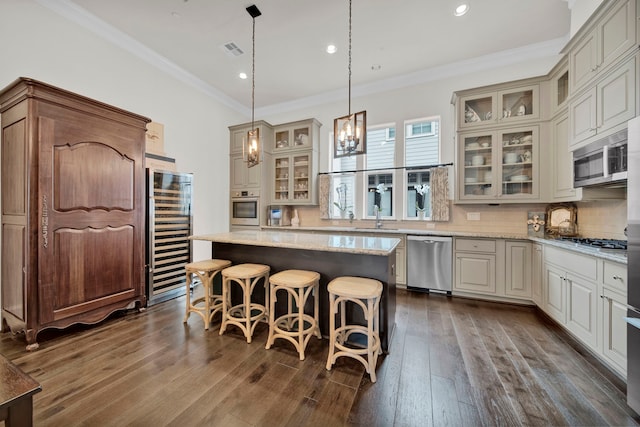 kitchen with a center island, stainless steel appliances, wine cooler, light stone counters, and decorative light fixtures