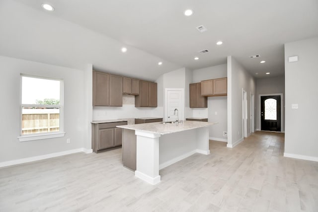 22022 Villa Terrace Dr, Hockley, TX 77447 - kitchen with sink, light hardwood / wood-style flooring, a center island with sink, and light stone countertops