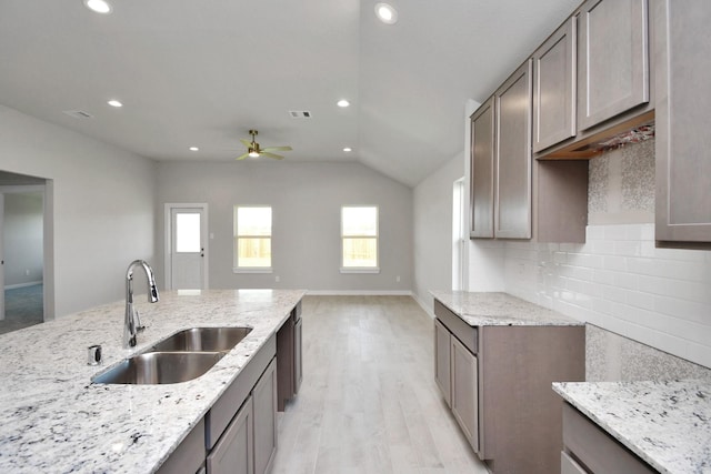 22022 Villa Terrace Dr, Hockley, TX 77447 - kitchen featuring sink, decorative backsplash, light stone counters, light hardwood / wood-style floors, and ceiling fan