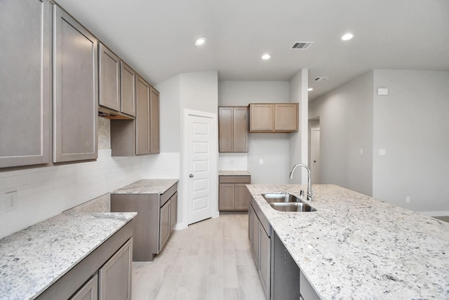 22022 Villa Terrace Dr, Hockley, TX 77447 - kitchen with sink, light stone countertops, light wood-type flooring, and backsplash