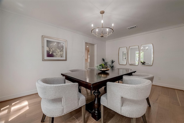 dining space with a chandelier, light wood-type flooring, and crown molding