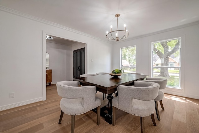 dining area with light wood-type flooring, ornamental molding, and an inviting chandelier