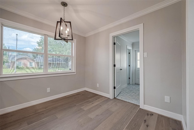 unfurnished dining area with a healthy amount of sunlight, an inviting chandelier, ornamental molding, and wood-type flooring