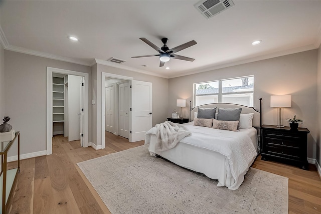 bedroom featuring ornamental molding, ceiling fan, light hardwood / wood-style flooring, a spacious closet, and a closet