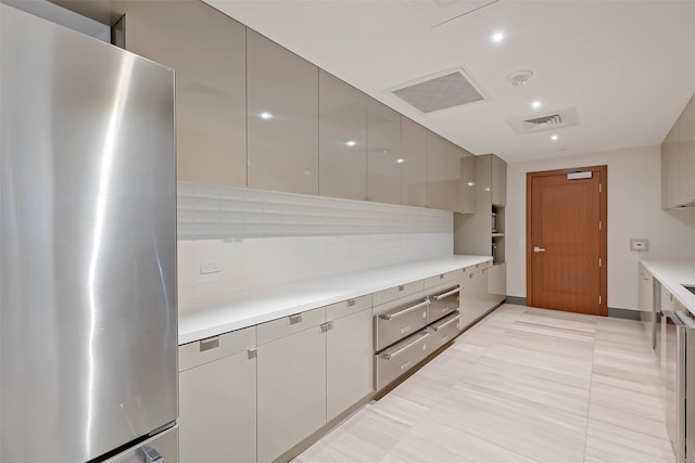 kitchen with gray cabinetry, stainless steel fridge, decorative backsplash, and light tile patterned flooring