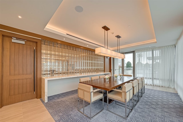 dining space with dark tile patterned floors and a raised ceiling