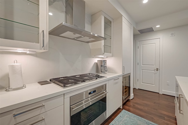 kitchen featuring wine cooler, wall chimney exhaust hood, dark hardwood / wood-style floors, stainless steel appliances, and white cabinets