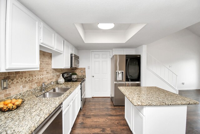 kitchen featuring appliances with stainless steel finishes, sink, a raised ceiling, light stone countertops, and dark wood-type flooring