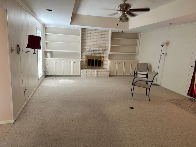 unfurnished living room with a fireplace, light colored carpet, ceiling fan, and wooden walls