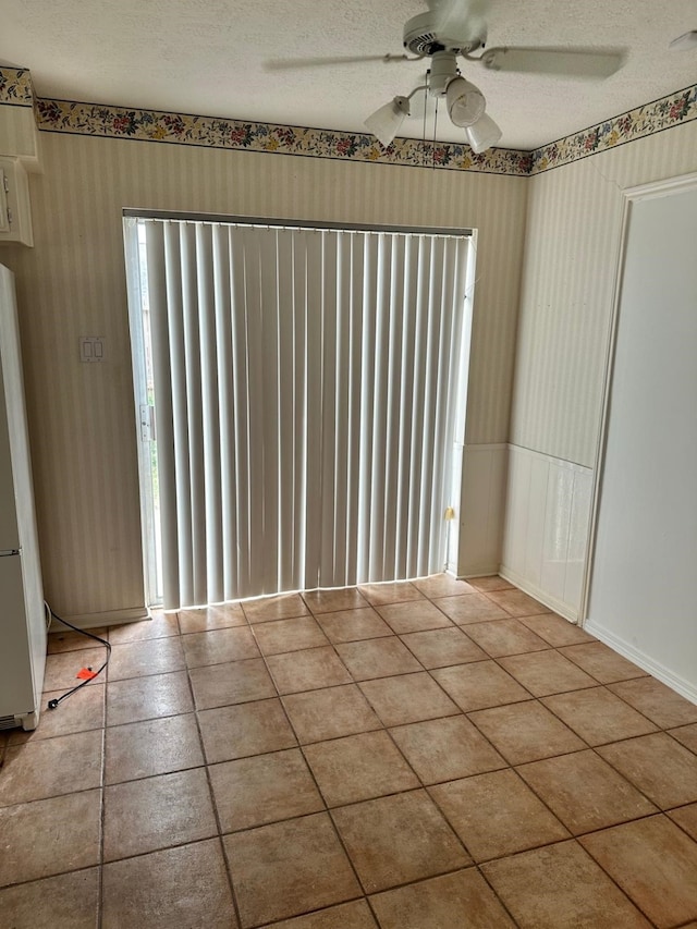 empty room featuring ceiling fan, a textured ceiling, and light tile patterned flooring