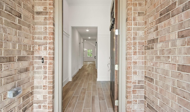 corridor featuring brick wall and hardwood / wood-style floors