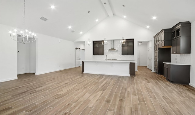 kitchen with decorative light fixtures, tasteful backsplash, light hardwood / wood-style floors, a barn door, and a spacious island