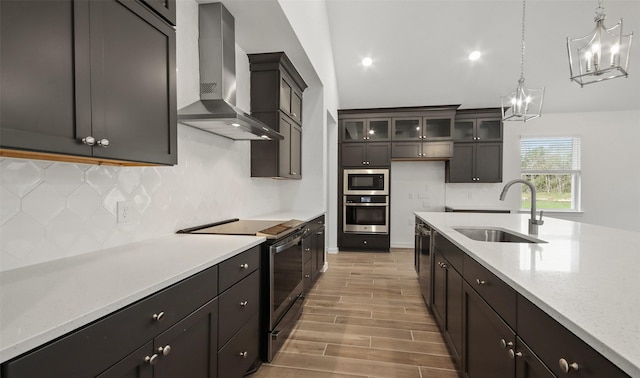 kitchen featuring pendant lighting, sink, decorative backsplash, stainless steel appliances, and wall chimney range hood