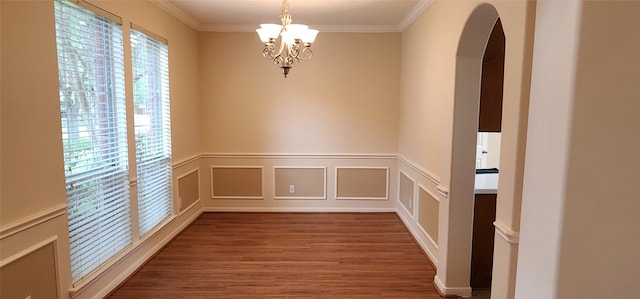 spare room with hardwood / wood-style floors, an inviting chandelier, and crown molding