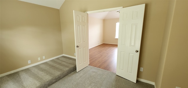 empty room featuring lofted ceiling and hardwood / wood-style flooring