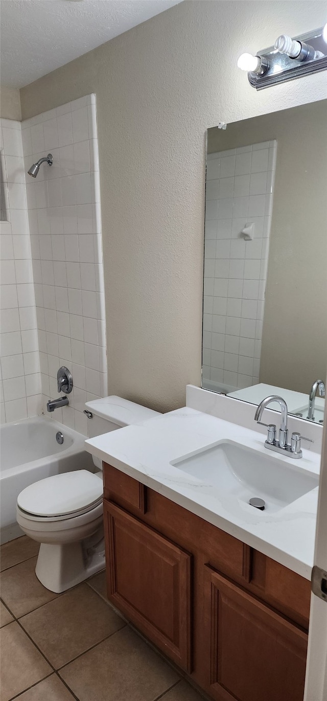 full bathroom with a textured ceiling, vanity, tile patterned flooring, toilet, and tiled shower / bath