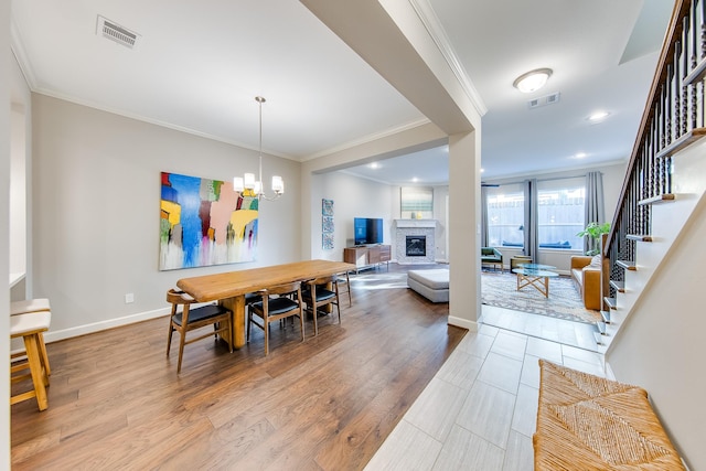 dining space with a glass covered fireplace, visible vents, a notable chandelier, and stairs