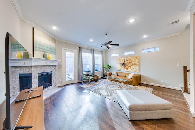 living room featuring ornamental molding, a tile fireplace, visible vents, and wood finished floors