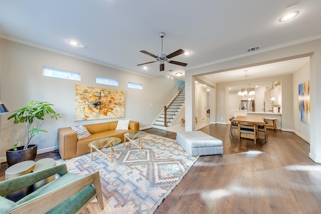 living area with baseboards, visible vents, stairway, wood finished floors, and crown molding