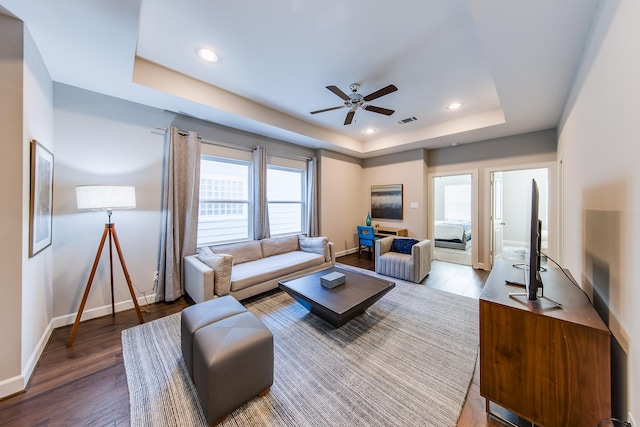 living room featuring wood finished floors, a raised ceiling, visible vents, and baseboards