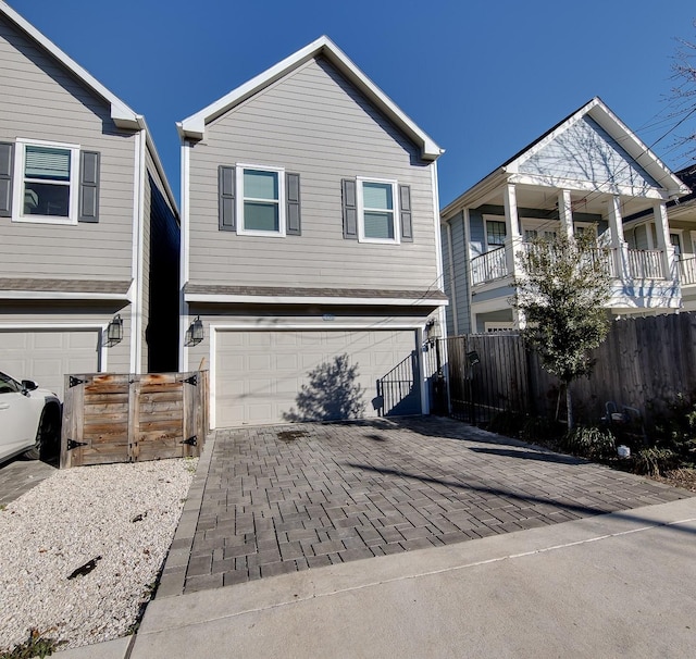 traditional-style house with a garage, decorative driveway, and fence