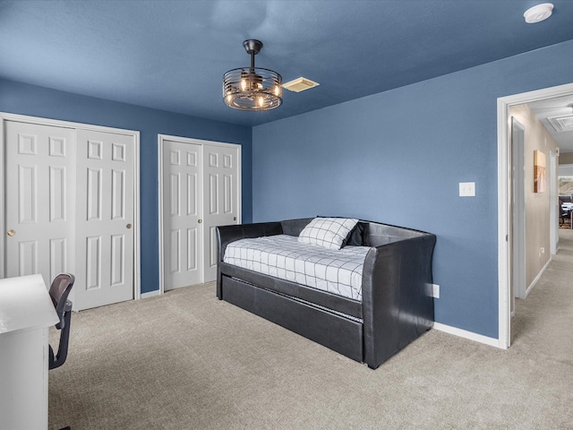 bedroom with two closets, light carpet, and ceiling fan