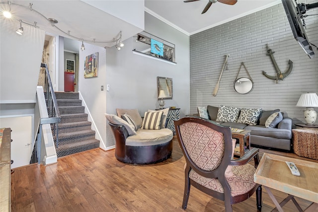 living room with hardwood / wood-style flooring, rail lighting, crown molding, and brick wall