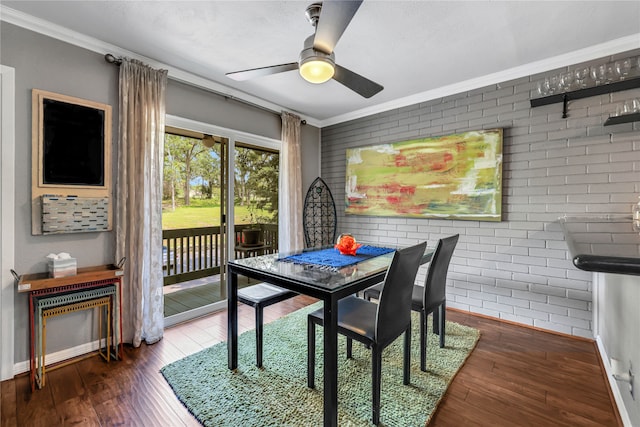 dining space with brick wall, ceiling fan, dark hardwood / wood-style flooring, and ornamental molding