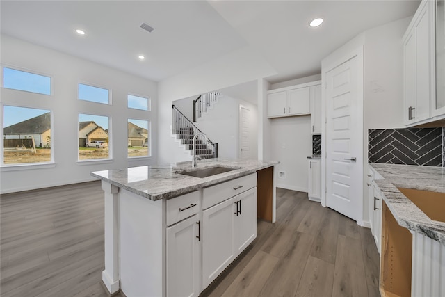 kitchen with light stone counters, light hardwood / wood-style floors, and white cabinets