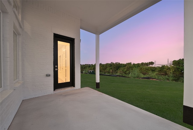 patio terrace at dusk featuring a yard