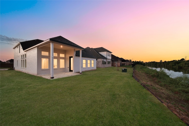 back house at dusk with a yard and a patio area