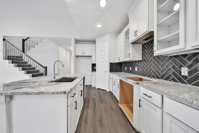 kitchen with dark hardwood / wood-style flooring, light stone counters, white cabinets, decorative backsplash, and sink