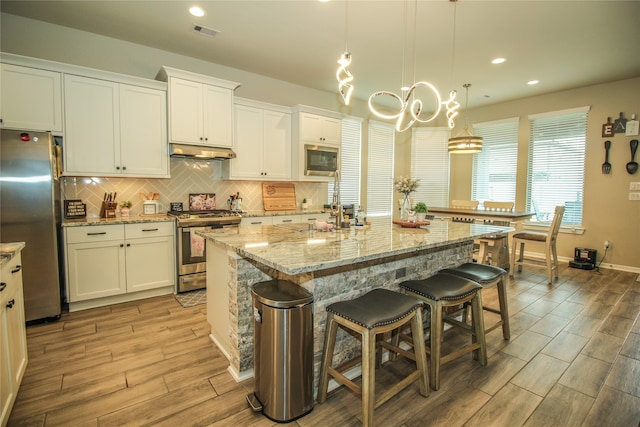 kitchen featuring appliances with stainless steel finishes, a kitchen island with sink, and white cabinets