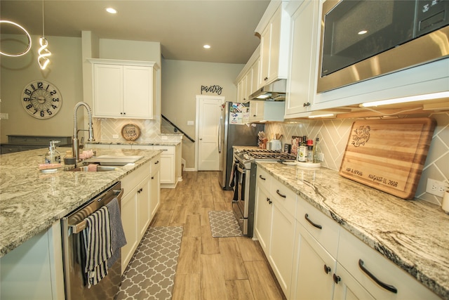 kitchen featuring light hardwood / wood-style floors, tasteful backsplash, decorative light fixtures, stainless steel appliances, and white cabinets