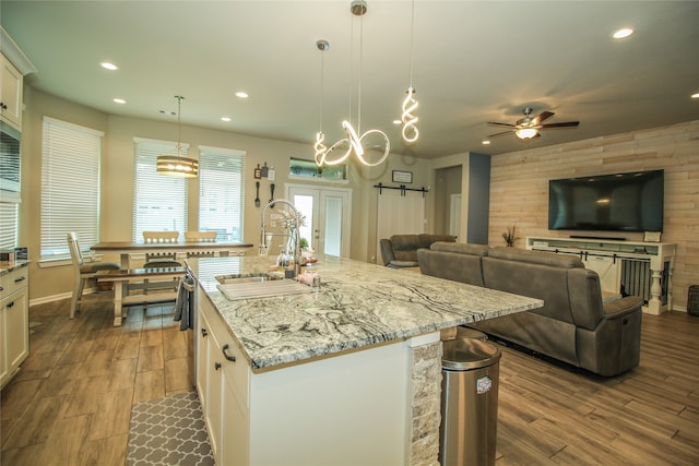 kitchen featuring pendant lighting, an island with sink, sink, and white cabinetry