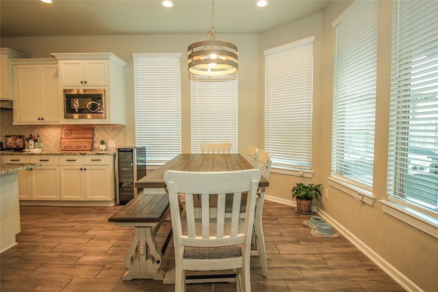 dining space with beverage cooler, a notable chandelier, and hardwood / wood-style flooring