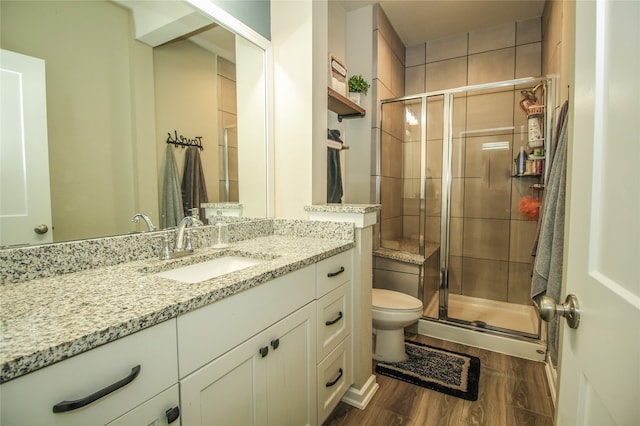 bathroom with an enclosed shower, wood-type flooring, vanity, and toilet