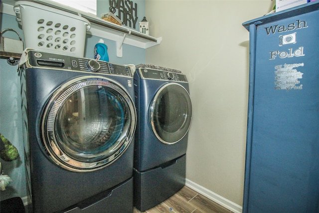 clothes washing area with independent washer and dryer and dark wood-type flooring