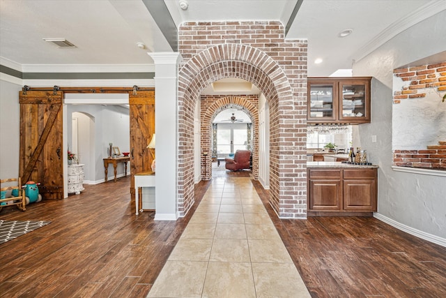 entryway with crown molding, dark hardwood / wood-style floors, and a barn door