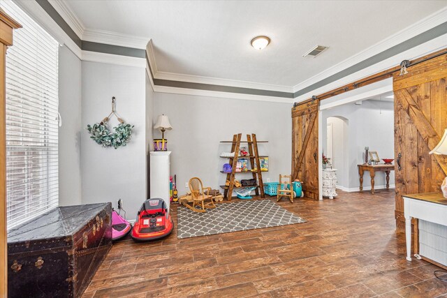 rec room with a barn door and ornamental molding