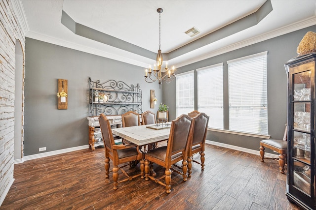 dining space featuring dark hardwood / wood-style flooring, a tray ceiling, a chandelier, and ornamental molding