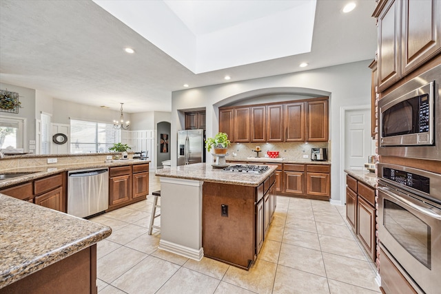 kitchen with a center island, an inviting chandelier, appliances with stainless steel finishes, light tile patterned floors, and hanging light fixtures