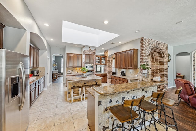 kitchen featuring backsplash, appliances with stainless steel finishes, kitchen peninsula, and a kitchen bar