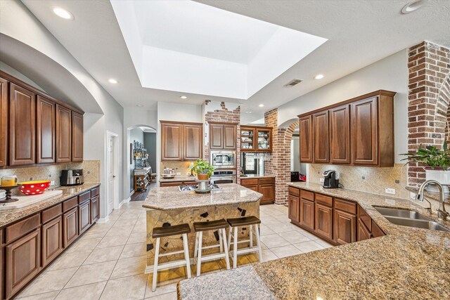 kitchen with a breakfast bar, sink, appliances with stainless steel finishes, tasteful backsplash, and a kitchen island