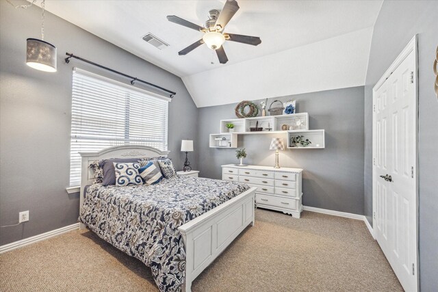 bedroom featuring ceiling fan, vaulted ceiling, light colored carpet, and a closet