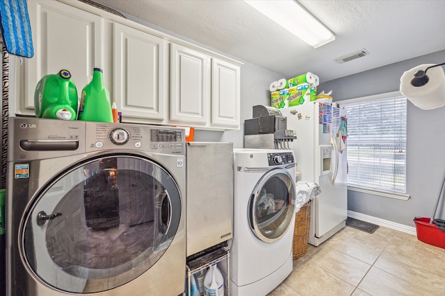 clothes washing area featuring washing machine and dryer, cabinets, and light tile patterned flooring