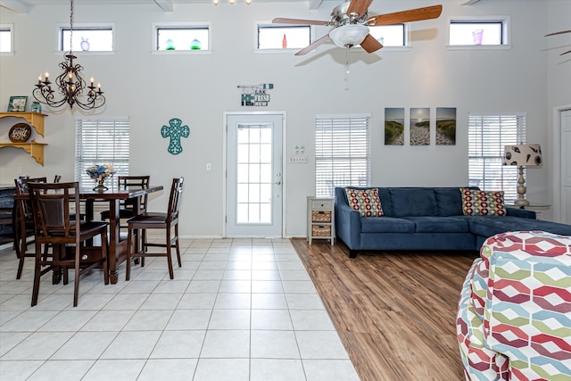 living room featuring a high ceiling, ceiling fan with notable chandelier, tile patterned floors, and a wealth of natural light